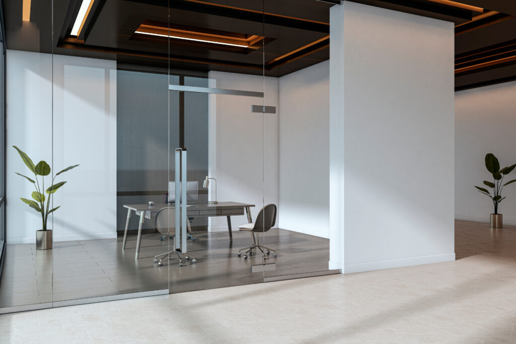 Modern office space showcasing architectural glass doors with glass walls and minimal furniture.